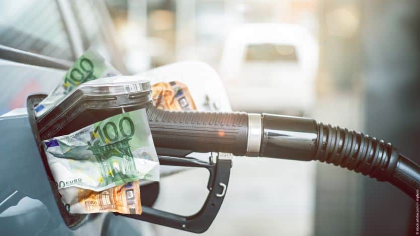 Eine Zapfhahn mit Geldscheinen steckt in der Tanköffnung, als Symbol für die steigenden Treibstoffpreise in Österreich