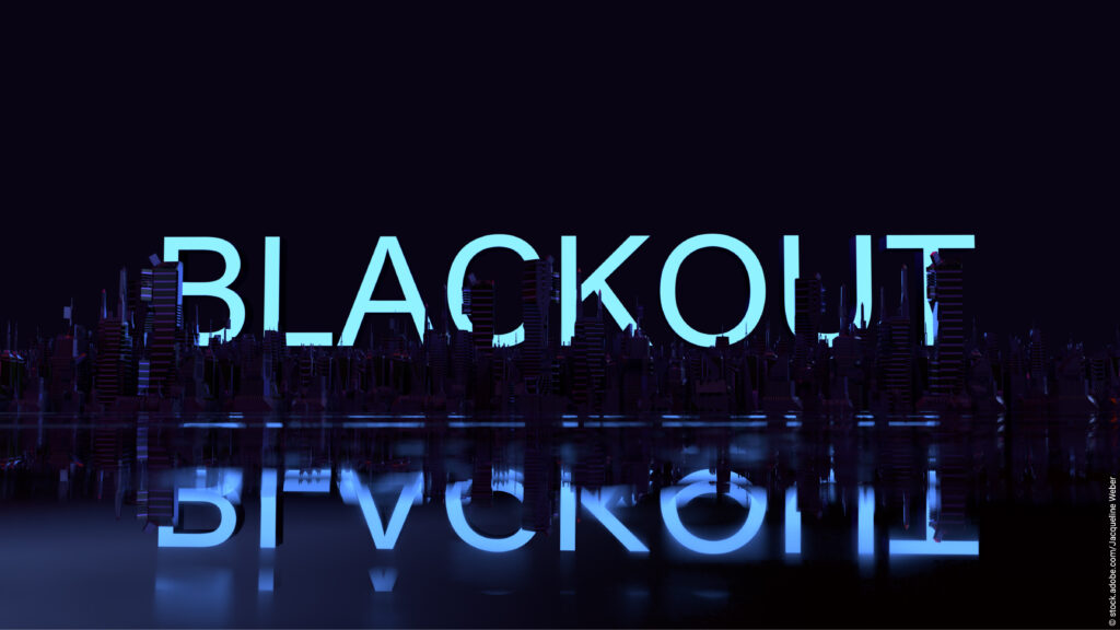 Düstere Skyline bei Nacht mit neon leuchtendem Schriftzug aus dem Wort Blackout