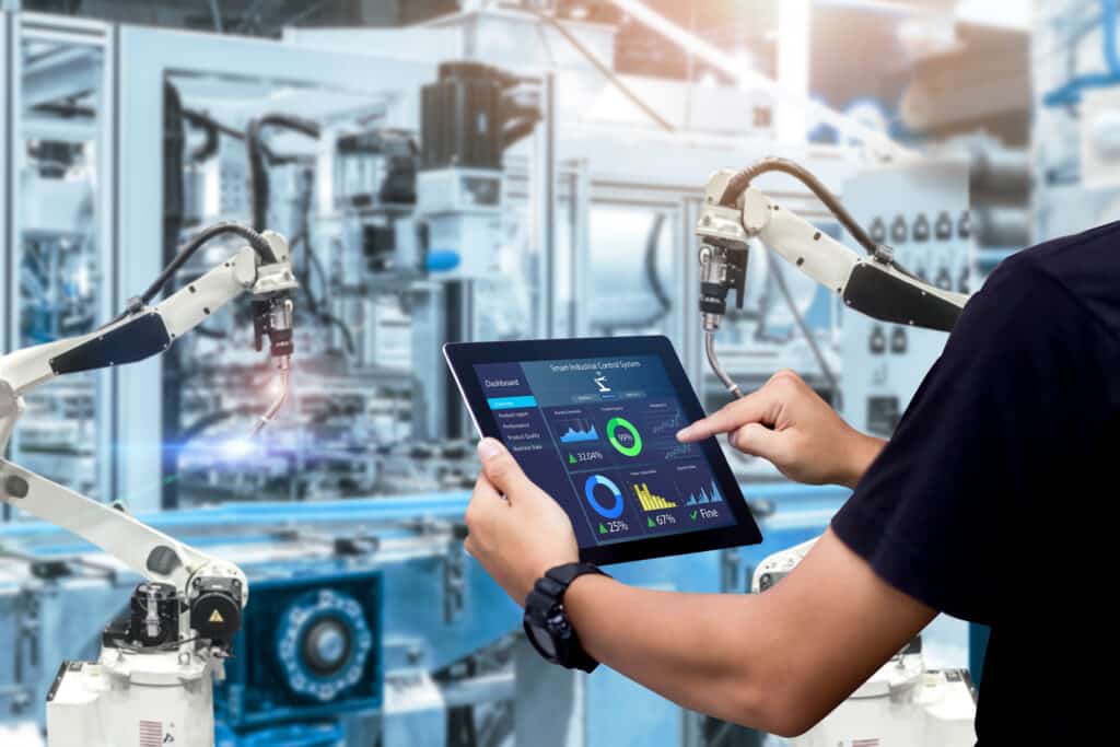 Intelligentes Industrie-Steuerungskonzept. Hände halten ein Tablet auf einer unscharfen Automatisierungsmaschine als Hintergrund.